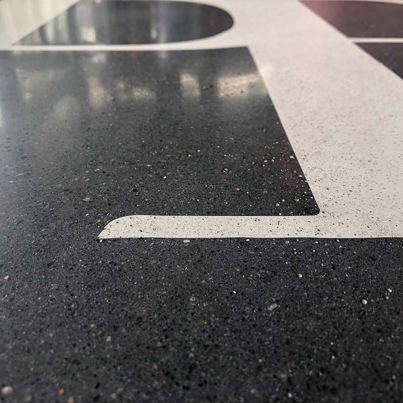 Terrazzo floor detail with dark logo inlay.